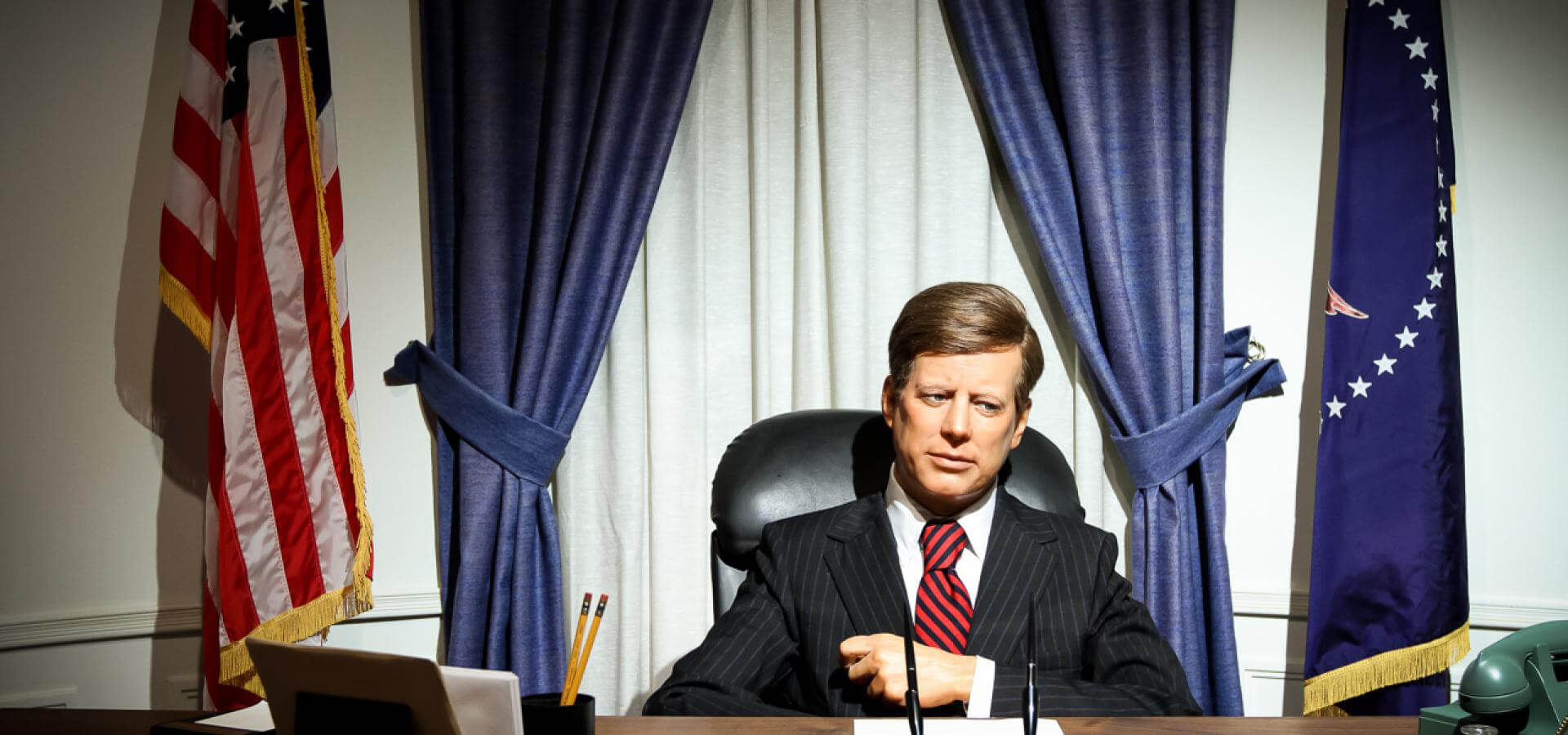 A slide of John F. Kennedy sitting at the Resolute Desk in the Oval Office of the White House. 