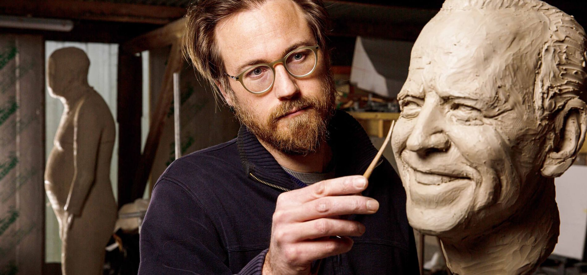 Artist nearing completion of the clay sculpture of Joe Biden's head.